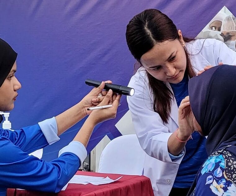 EyeCare Hospital doctor examining an elderly woman's eyes at Israhvehinge Ufaa, Vilingili
