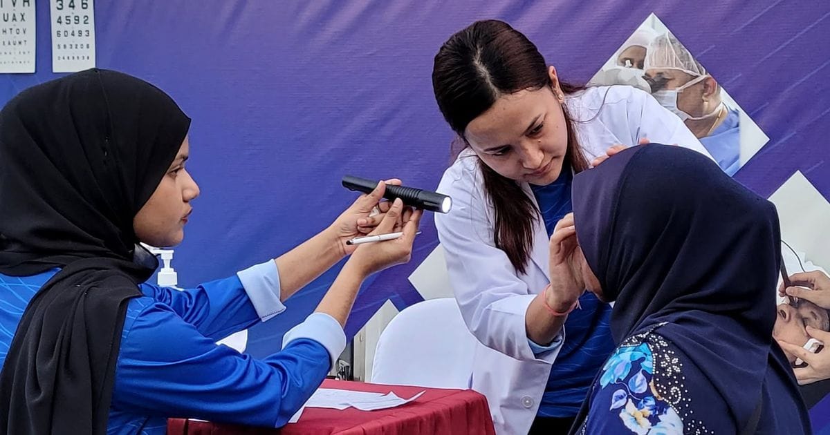 EyeCare Hospital doctor examining an elderly woman's eyes at Israhvehinge Ufaa, Vilingili